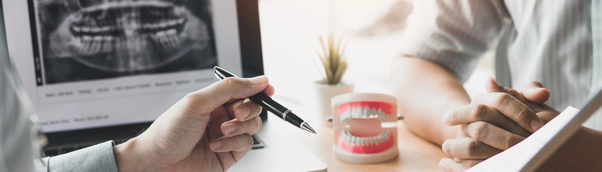 Gute Beratung zeichnet uns aus: Zu sehen ist ein Zahnarzt mit einem Stift in der Hand, der einem Patient etwas erlärt.